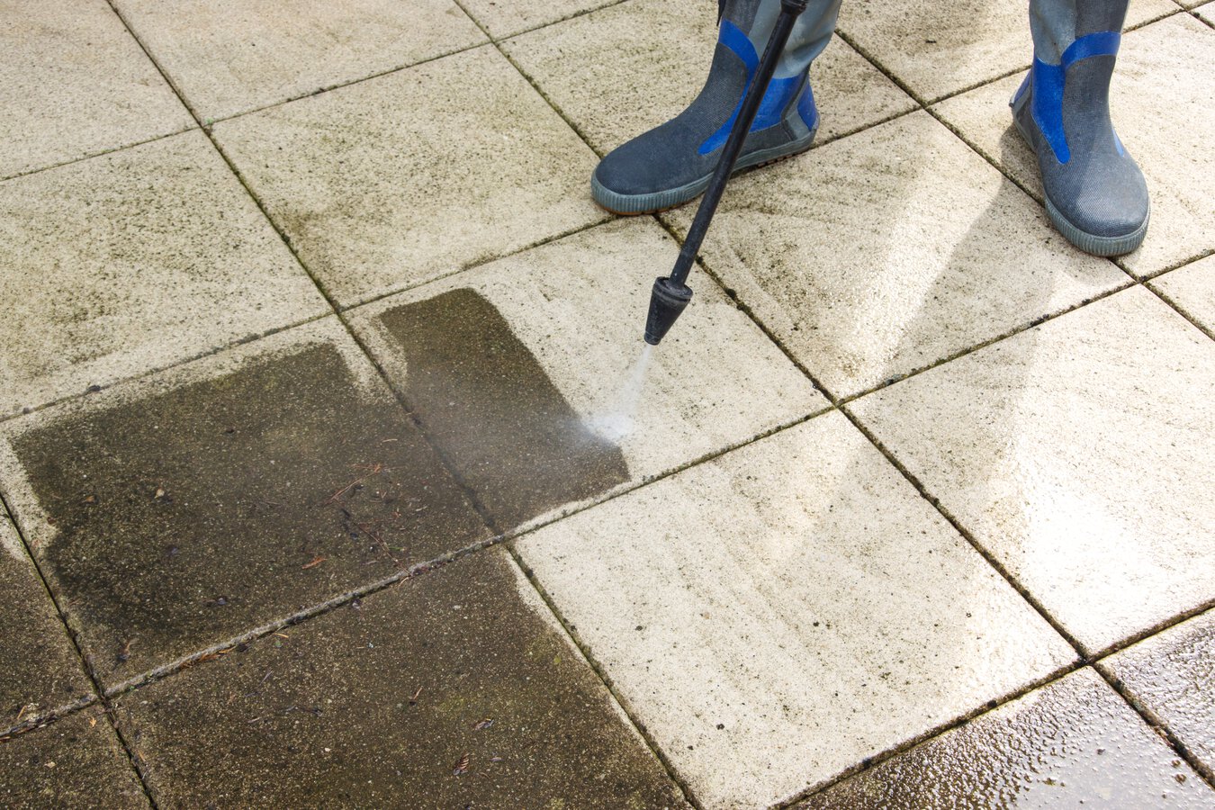 man power washing built up grime from a patio